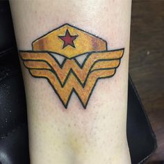 a wonder woman tattoo on the ankle with stars and wings above it's logo