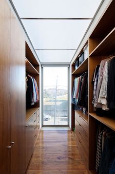 a walk - in closet with wooden cabinets and clothes on hangers, next to a sliding glass door