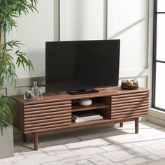 an entertainment center with a flat screen tv on it's stand in front of a window