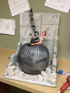 a statue of a woman sitting on top of a giant ball with chains hanging from it