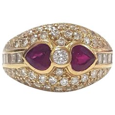 A lady's ruby and diamond ring set in 18 Karat yellow gold. Contemporary style. Featuring a pair of bezel set heart shaped rubies, east west mounted between a small bezel set round brilliant cut diamond and flanked by channel set baguette cut diamonds. The low domed head is also embellished with pave' set round brilliant cut diamonds. The shank is tapered. Used. Total number of stones: 73 Total number of diamonds: 71 Total weight: 1.15 ct. approx. Color: G-H Clarity: VS1-VS2 Total ruby weight: 1 Luxury Unique Ruby Ring With Bezel Setting, Luxury Elegant Ruby Ring With Bezel Setting, Luxury Modern Ruby Ring With Bezel Setting, Luxury Ruby Jewelry With Bezel Setting, Luxury Ruby Ring With Bezel Setting, Luxury Ruby Ring With Bezel Setting For Wedding, Luxury Open Ruby Ring With Bezel Setting, Luxury Antique Ruby Ring With Bezel Setting, Luxury Bezel Set Ruby Ring For Formal Occasions