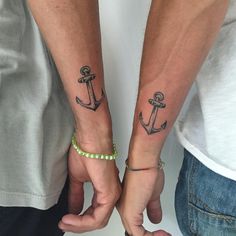 two people are holding hands with tattoos on their arms and one has an anchor tattoo