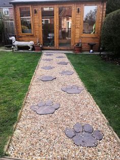 a dog's paw prints are on the gravel in front of a wooden cabin