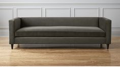 a gray couch sitting on top of a hard wood floor next to a white wall