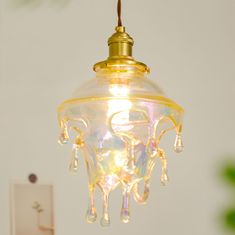 a yellow light hanging from a ceiling in a room with white walls and green plants