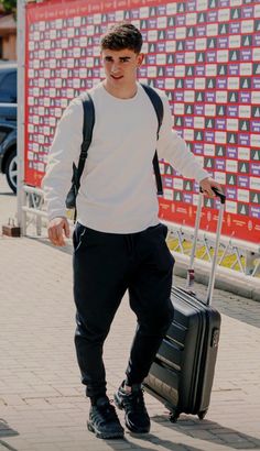 a young man walking down the street with his luggage