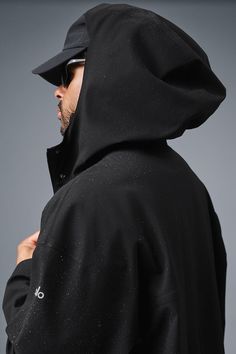 Stay dry without compromising style in this coat. It's stacked with functional features like a tall collar, a hood with bungees, zippered side pockets, and a secure zipper-and-snap front. Plus, it's made from soft, lightweight, 100 percent waterproof ripstop with a relaxed fit to accommodate movement. Cool on the streets? Yes. Suitable for stormy days? Also yes. Alo Yoga Hooded Outerwear For Winter, Alo Yoga Winter Streetwear Outerwear, Oversized Functional Outerwear With Drawstring Hood, Alo Yoga Oversized Long Sleeve Outerwear, Urban Black Raincoat For Fall, Sporty Hooded Alo Yoga Outerwear, Alo Yoga Winter Outdoor Outerwear, Modern Black Parka With Detachable Hood, Outdoor Long Coat Hooded Jacket With Detachable Hood