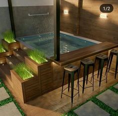 an outdoor hot tub with three stools next to it and grass growing on the floor