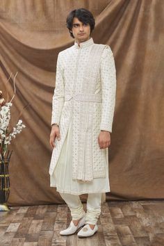 Crystal cream embroidered sherwani in geometric thread work. Paired with an embroidered placket kurta, churidar pant and dupatta. Comes with kamarbandh.
Component: 5
Pattern: Embroidered
Type Of Work: Thread work
Neckline: Mandarin collar
Sleeve Type: Full sleeves
Fabric: Raw silk, Mysore silk
Color: White
Other Details: 
Embroidered kamarbandh and dupatta
Occasion: Wedding,Groom - Aza Fashions Embroidered Sherwani, Mysore Silk, Mysore, Thread Work, Churidar, Full Sleeves, Wedding Groom, Embroidered Silk, Raw Silk