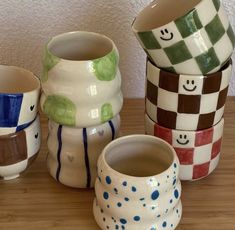 five different colored ceramic cups sitting on top of a wooden table next to each other