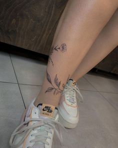 a woman's legs with flowers on them and a tattoo on the lower part of her leg