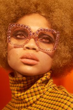 a woman with an afro wearing glasses and a scarf