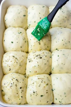 a green spatula in a white casserole dish filled with rolls