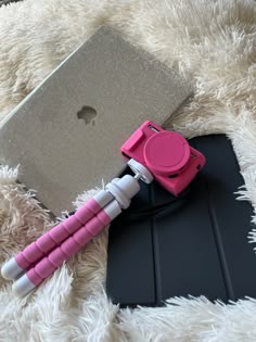 a pink and white pen sitting on top of a black mat next to an apple laptop