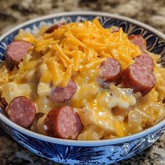 a blue and white bowl filled with macaroni and cheese, sausage and cheddar