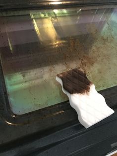 a piece of white and brown paper sticking out of an oven door with rust on it