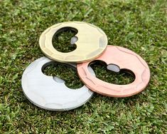 three different colored bottle openers sitting in the grass