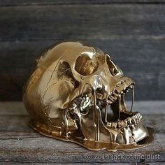 a gold colored skull sitting on top of a wooden table