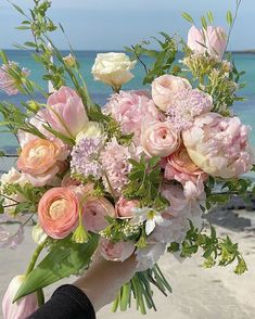 a person holding a bouquet of flowers on the beach