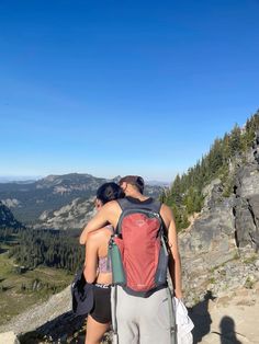 two people standing on top of a mountain with backpacks