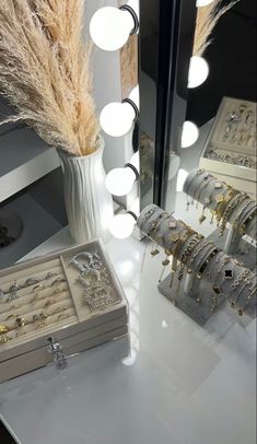 a white vase filled with lots of jewelry sitting on top of a table next to a mirror