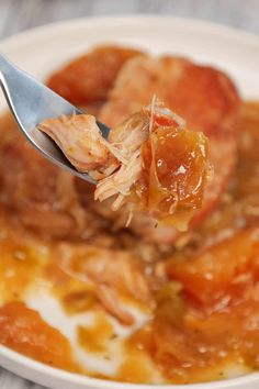 a spoonful of food is being held up over the bowl with meat and vegetables