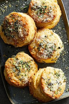 four small pastries on a baking sheet with parmesan sprinkles