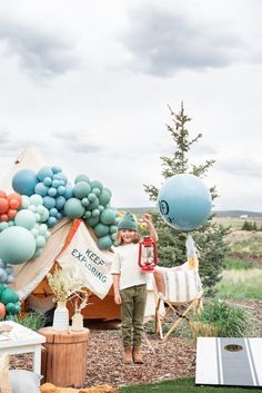 a woman standing in front of a tent with balloons