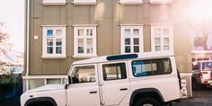 a white land rover parked in front of a building with windows on the side of it