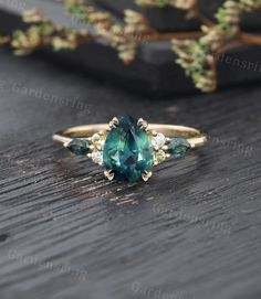 a ring with an oval cut green stone surrounded by three small diamonds on a wooden surface