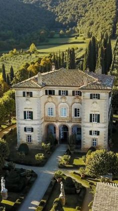 an aerial view of a large house surrounded by trees and bushes in front of a lush green hillside