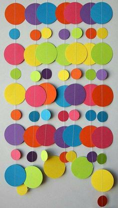 colorful paper circles are hanging on a white wall and there is no image to describe