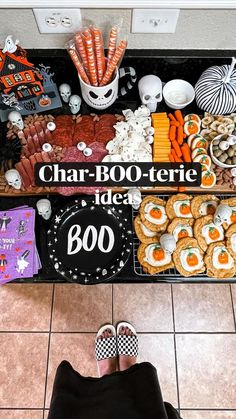 a person standing in front of a table filled with halloween food and decorations on it