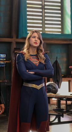 the supergirl is standing with her arms crossed