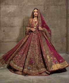 a woman in a red and gold bridal gown posing for the camera with her hands on her hips