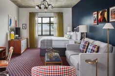 a living room filled with furniture next to a bed and a desk in front of a window