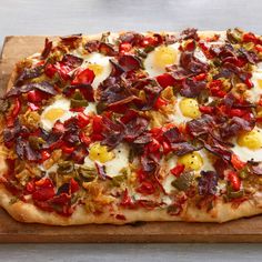 a pizza topped with bacon and eggs on top of a wooden cutting board