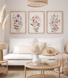 a living room filled with white furniture and paintings on the wall above it's coffee table