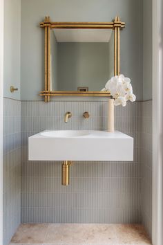 a white sink sitting under a mirror next to a wall mounted faucet in a bathroom