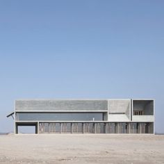 the building is made out of concrete and sits on top of a sandy area with no grass