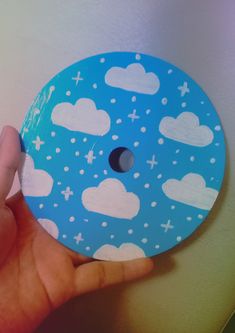 a hand holding a blue and white disc with clouds on it