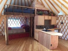 the interior of a yurt with wood flooring and wooden furniture, including a bed