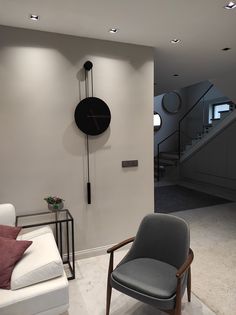 a living room filled with furniture and a clock mounted to the side of the wall