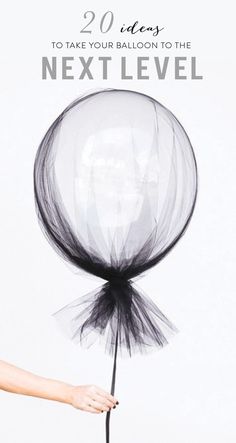 a hand holding a black and white balloon with tulle on it's tail