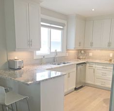 a kitchen with white cabinets and marble counter tops, along with two bar stools