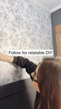 a woman is painting a wall with white flowers on it and the words follow for reliable diy