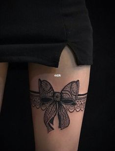 a woman's thigh with a bow tattoo on it