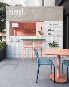 the outside of a restaurant with tables and chairs in front of it, along with plants