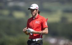 a man in red shirt and black pants holding a golf club