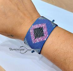 a person wearing a blue bracelet with pink and black designs on it's wrist